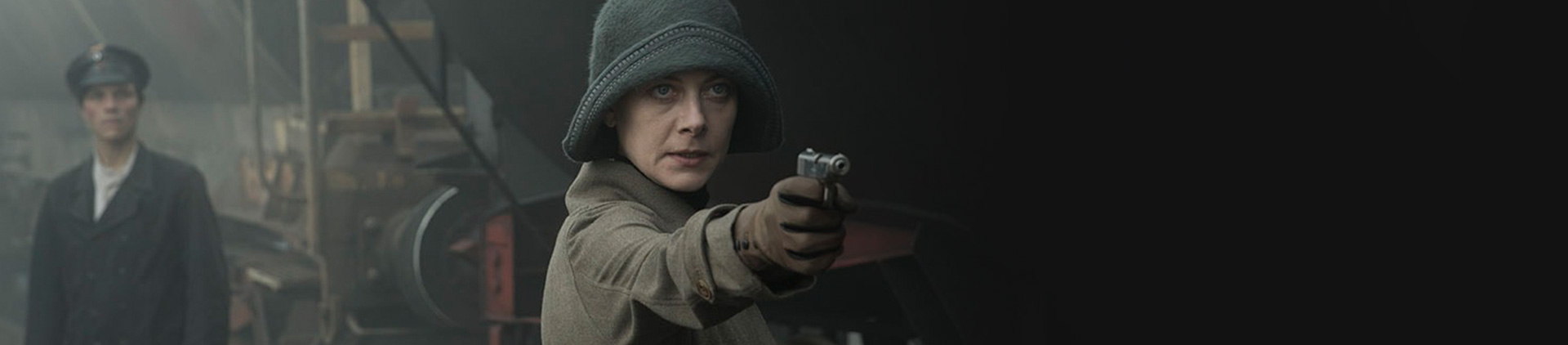 Cena de um filme em que uma mulher aponta um revólver. Ela está caracterizada nos anos 20.