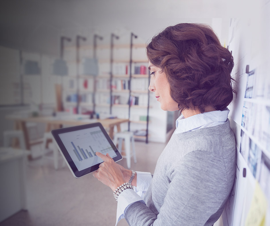 Foto de uma mulher em ambiente de trabalho analisando um gráfico no tablet.