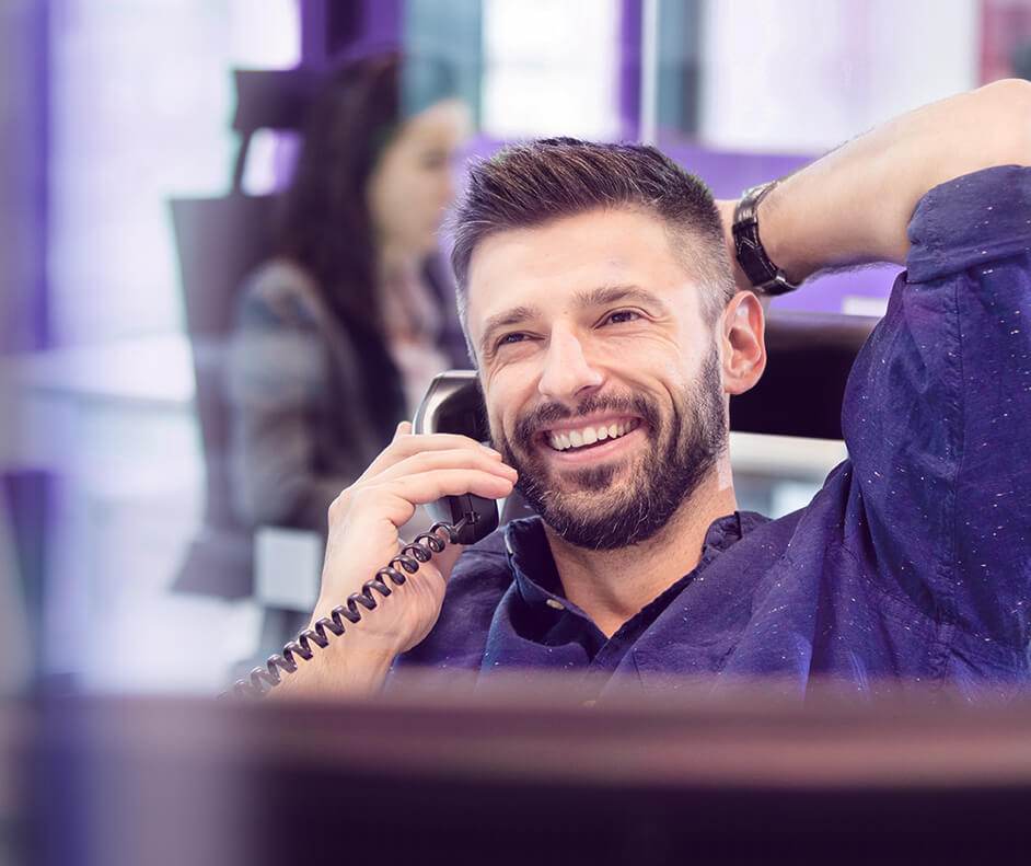 Foto de homem falando ao telefone em ambiente corporativo.