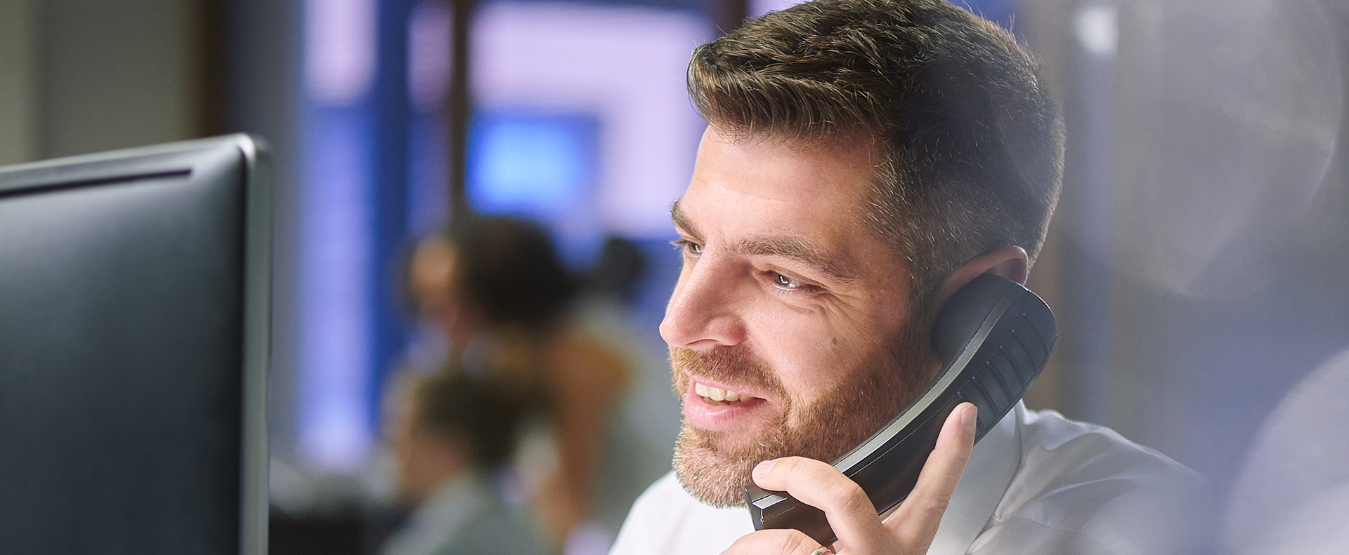 Imagem de homem falando ao telefone em ambiente corporativo.