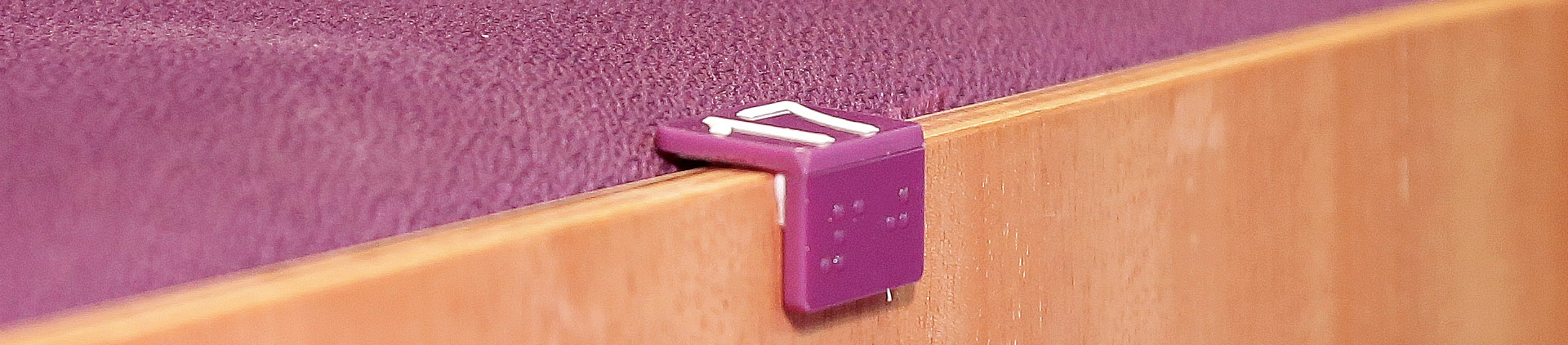 Imagem de um marcador de poltrona da sala de espetáculos com sua numeração em numeral e em braile.