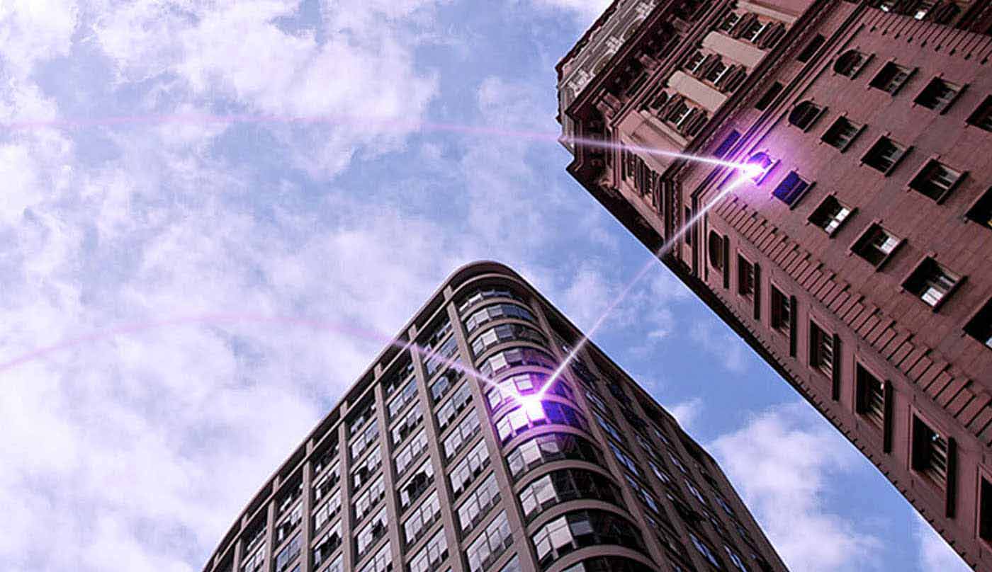 Imagem de dois prédios interligados por um rastro luminoso púrpura.