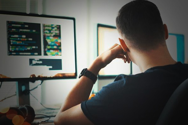 Imagem de um homem de costas utilizando o computador.