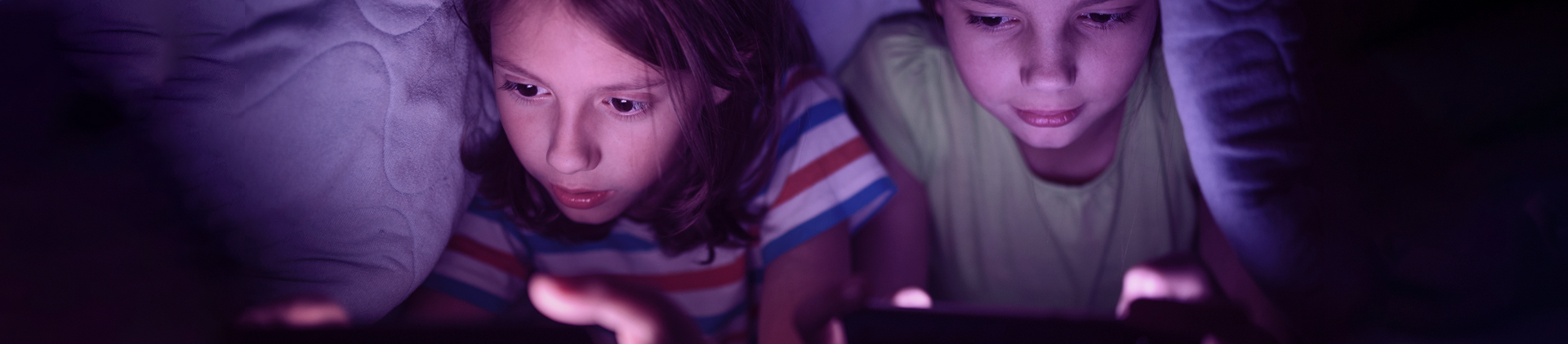 Duas crianças, uma menina e um menino, concentrados jogando jogos no celular