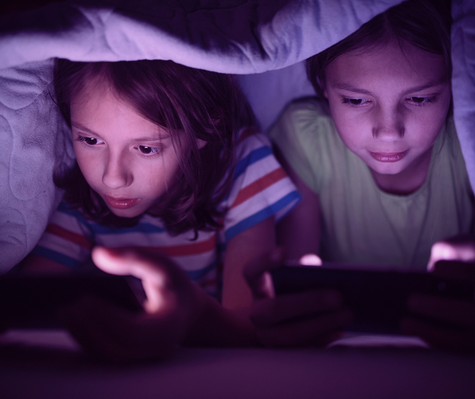 Duas crianças, uma menina e um menino, concentrados jogando jogos no celular