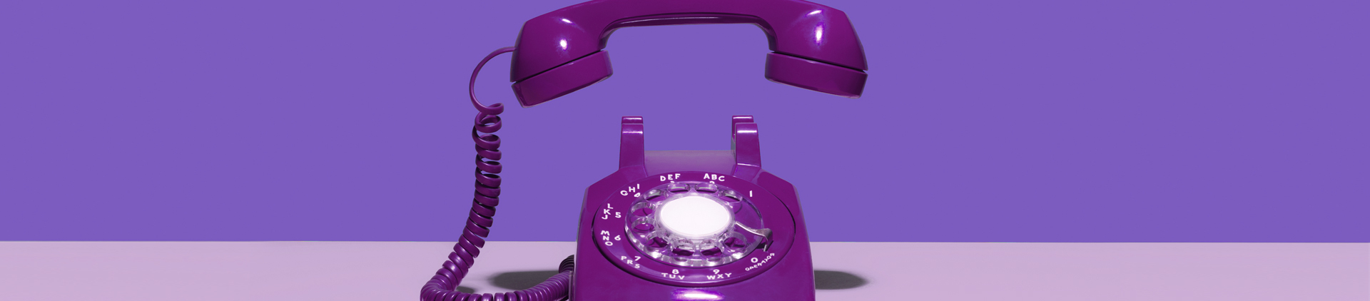 Telefone fixo pintado de roxo. Ele está tocando