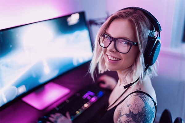 Mulher utilizando acessórios gamer enquanto mexe no computador.