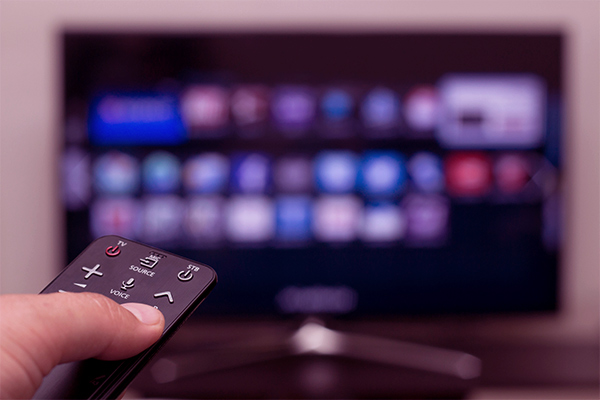 Imagem de uma pessoa apontando um controle remoto para a TV.