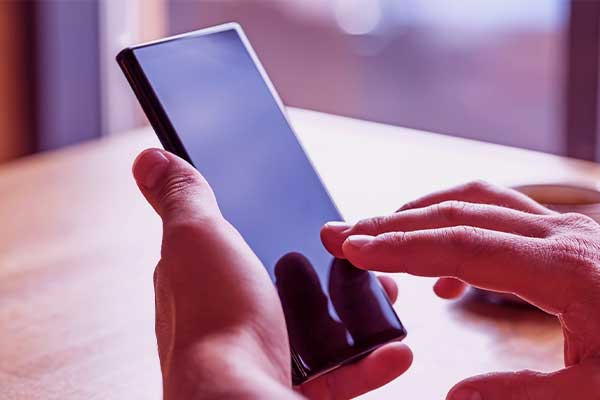 Mão tentando destravar o celular por não ter realizado a atualização. 