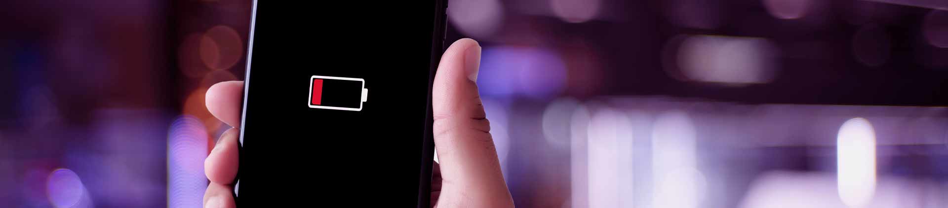 Pessoa segurando celular. Na tela, uma ilustração mostrando que a bateria está acabando