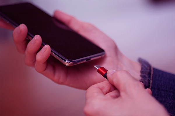 Mão conectando um carregador em um iPhone