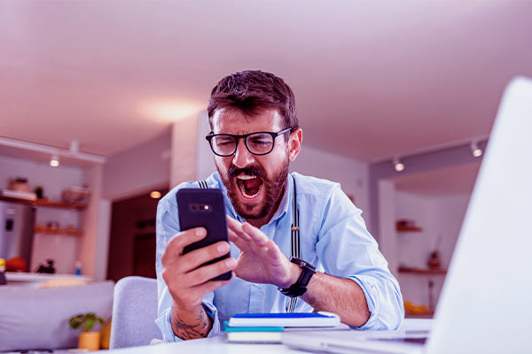 Homem gritando enquanto segura um celular que está travando