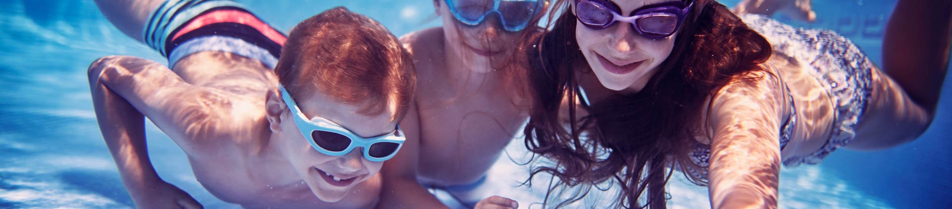 Imagem de três crianças tirando uma selfie na piscina.
