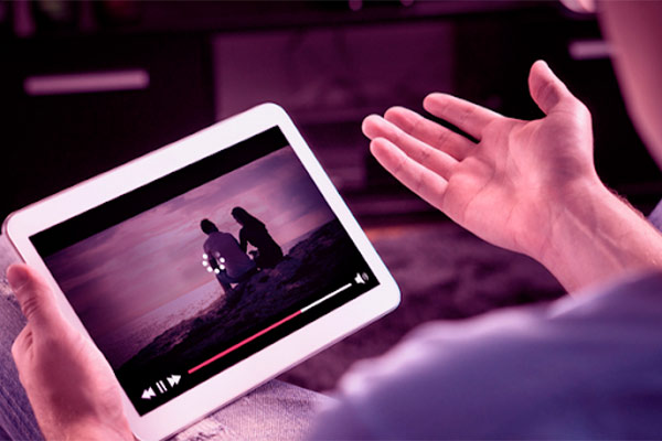 Homem segurando um tablet vendo filme travado com símbolo de carregamento na tela