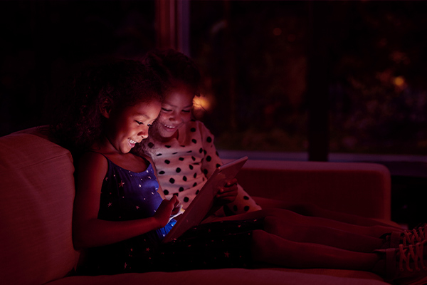 Imagem de duas crianças brincando com um tablet.