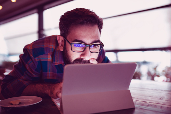 Imagem de um homem olhando para a tela de um notebook.