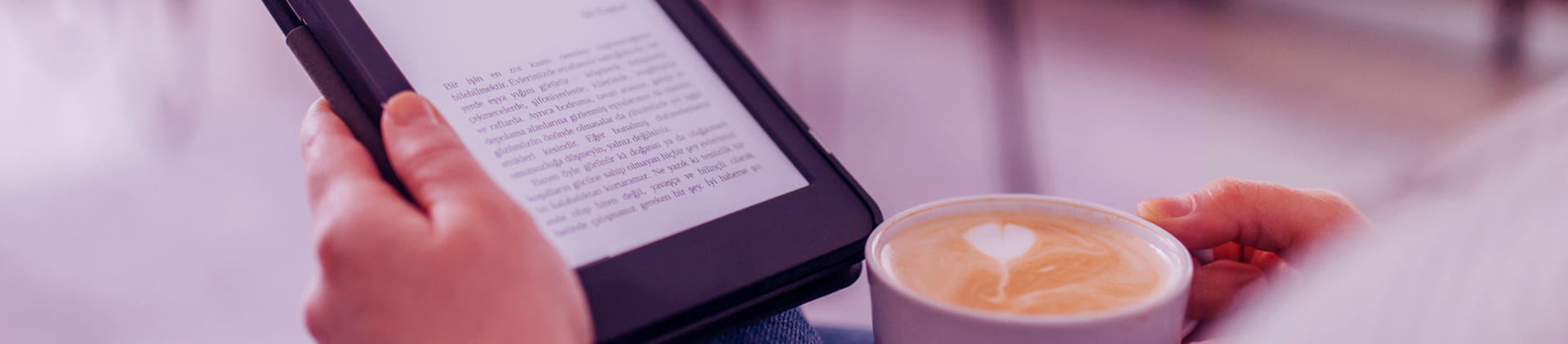 Pessoa tomando um café expresso enquanto lê livro no kindle. Ela está sentada no sofá