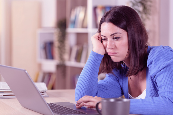 Imagem de uma mulher usando o notebook com uma expressão frustrada.