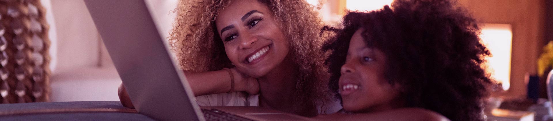 duas mulheres sorrindo e testando a velocidade de download e upload em frente ao computador