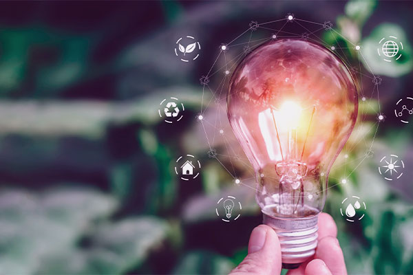 Mão segurando uma luz acesa com ícones que promovem o melhor uso das fontes de energia. 
