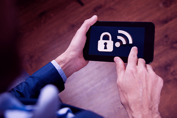 Imagem de um homem usando um tablet, onde é exibido um ícone de senha para wi-fi.