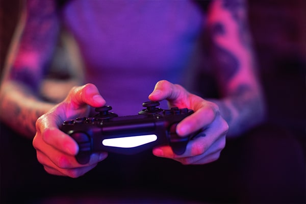 Foco nas mãos de uma pessoa segurando um controle de videogame com f