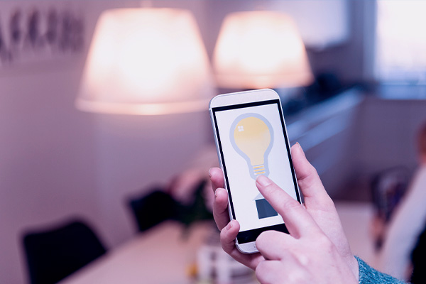 Mão segurando um smartphone enquanto controla lâmpada inteligente no aplicativo
