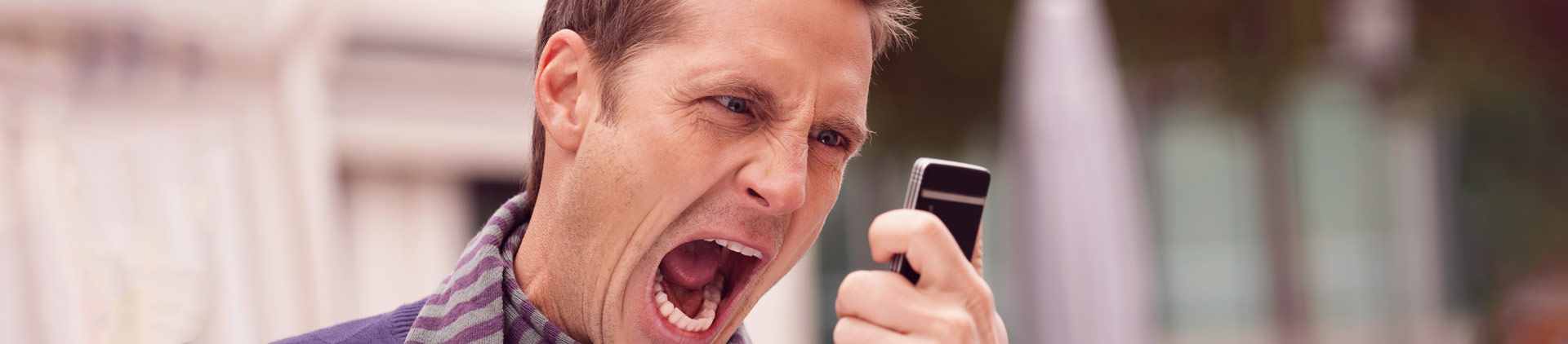 Homem gritando para o celular com uma ligação indesejada