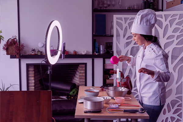 Imagem de uma chef gravando um vídeo ensinando uma receita.