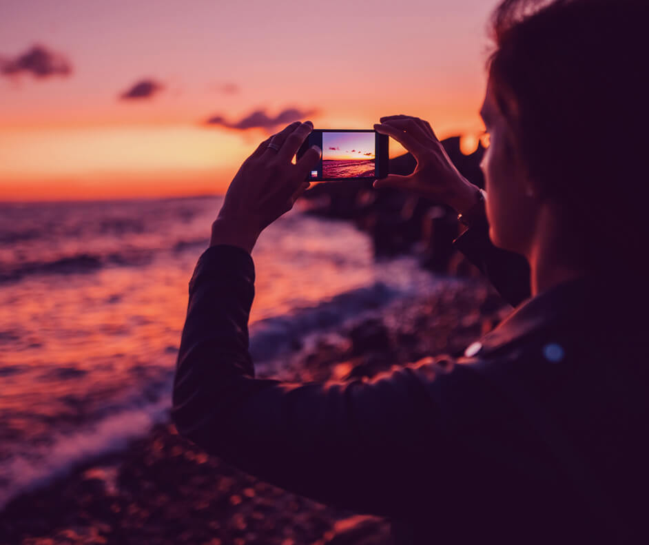 Pessoa fotografando o mar ao pôr do sol