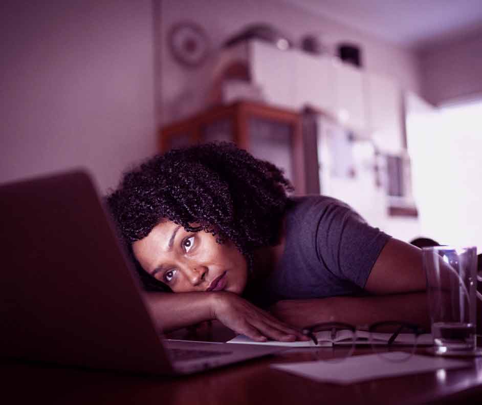 Moça impaciente com a velocidade do notebook. Ela está deitada, pensado em formas de deixá-lo mais r