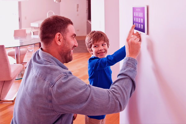 Imagem de pai e filho ajustando dispositivos conectados da casa em um tablet.