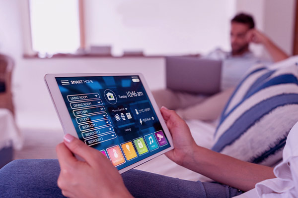 Imagem de uma pessoa controlando os dispositivos conectados de sua casa pelo tablet.