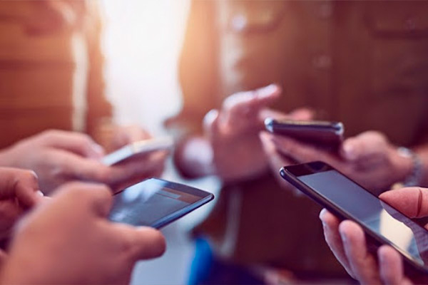 Imagem de 4 pessoas, centralizada somente nas mãos mexendo no celular. 