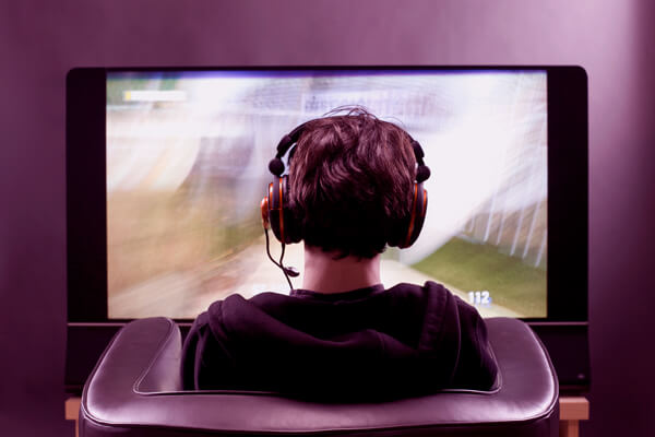 Imagem de um rapaz de costas jogando videogame