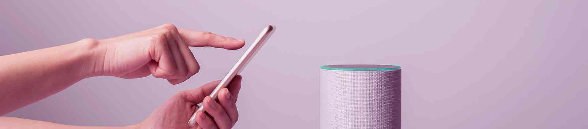 Smarthphone sendo utilizado para tirar foto de uma caixa de som que possui inteligência artificial.