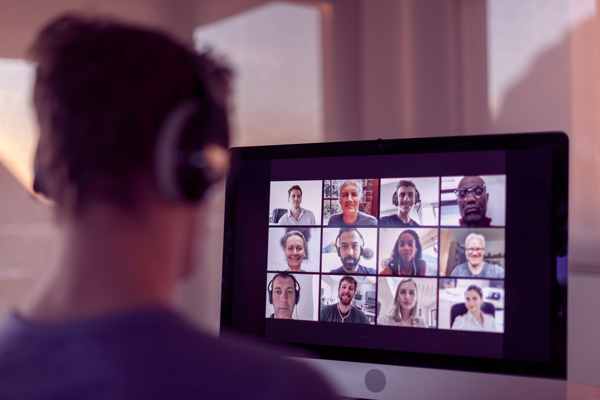 Imagem de um homem usando o computador, enquanto participa de uma videoconferência com 12 pessoas.