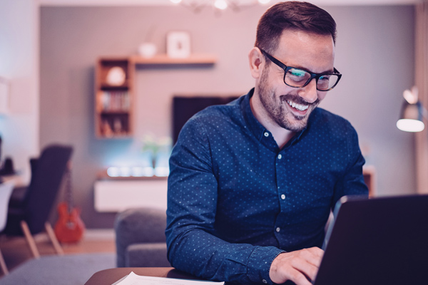 Imagem de um homem sorrindo enquanto usa um notebook.