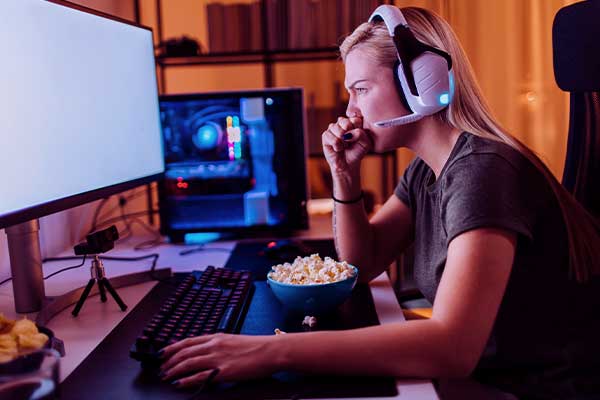 Moça com um headphone em uma mesa comendo pipoca e jogando em um PC gamer com upgrade
