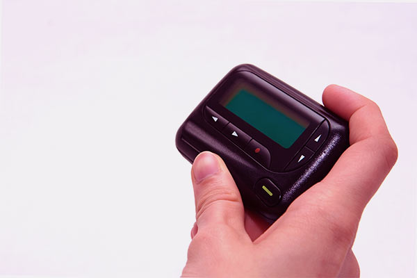Mão de um home segurando um bipe, também conhecido como pager