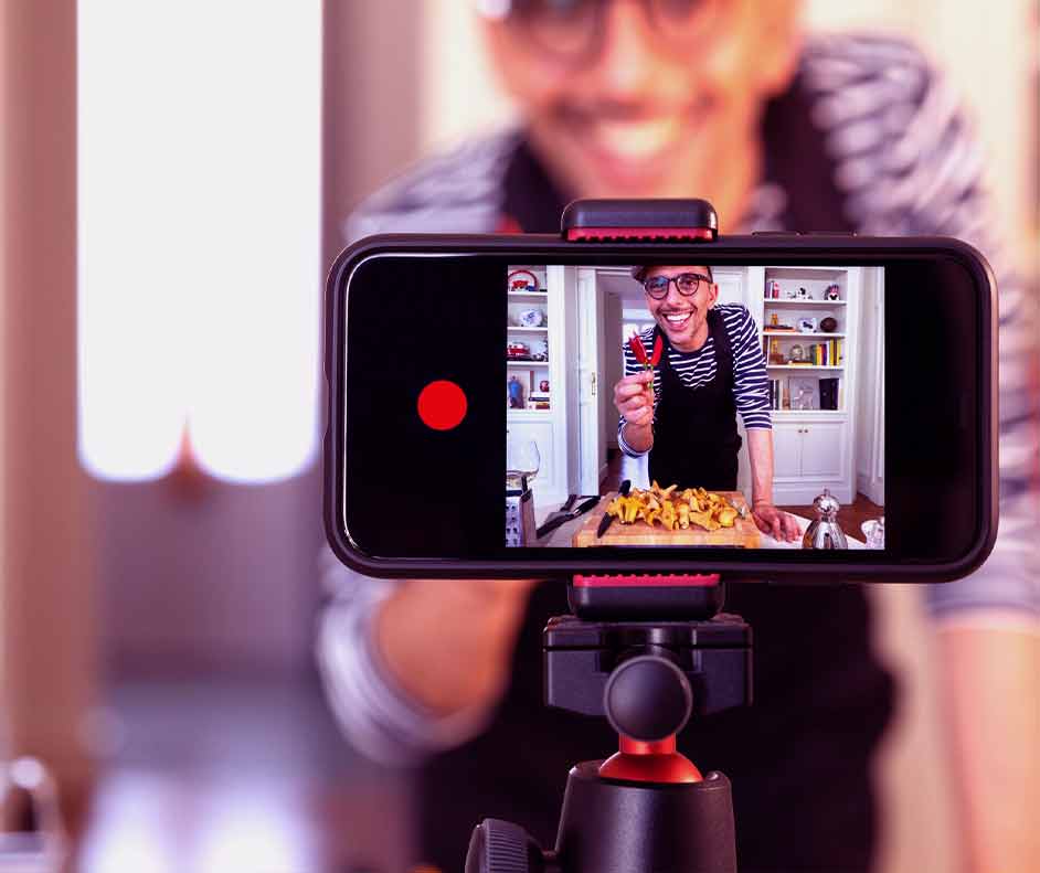 Homem gravando um vídeo no celular em câmera lenta. Parece uma receita culinária