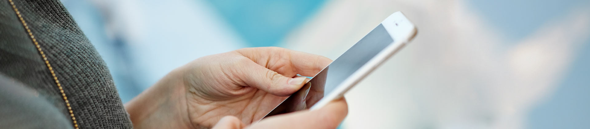 Imagem em close das mãos de uma mulher segurando um smartphone.
