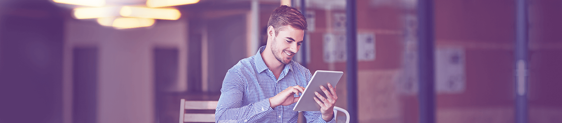 Foto de um homem sorrindo enquanto utiliza o tablet.